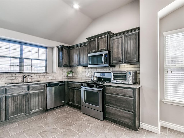 kitchen with lofted ceiling, a toaster, a sink, appliances with stainless steel finishes, and backsplash