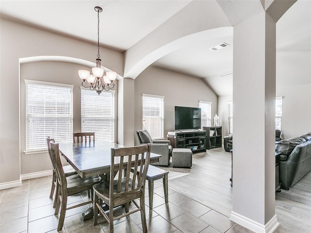 dining space with light tile patterned floors, baseboards, visible vents, arched walkways, and a notable chandelier