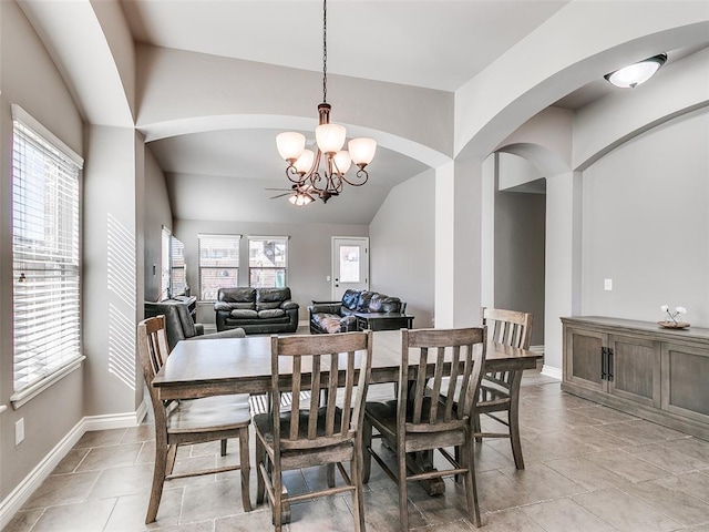 dining area with light tile patterned floors, baseboards, arched walkways, lofted ceiling, and a notable chandelier