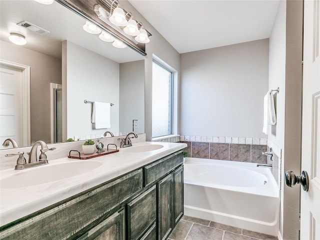 full bath with visible vents, double vanity, a sink, and a bath