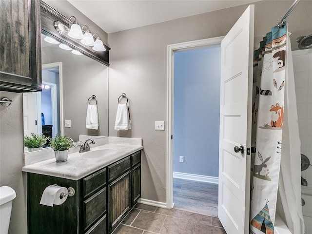 bathroom featuring shower / bath combination with curtain, toilet, vanity, and baseboards