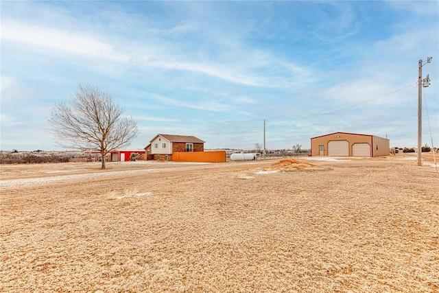 view of yard with an outbuilding, a rural view, a detached garage, and driveway