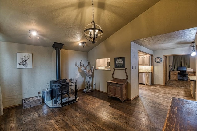 interior space featuring dark wood-style flooring, vaulted ceiling, a textured ceiling, and a wood stove