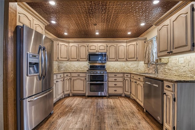 kitchen with stainless steel appliances, light brown cabinetry, a sink, and light stone countertops