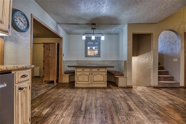 kitchen with dishwasher, a textured wall, dark wood-style flooring, decorative light fixtures, and a textured ceiling