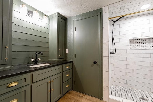 full bathroom with a textured ceiling, a stall shower, wood finished floors, and vanity