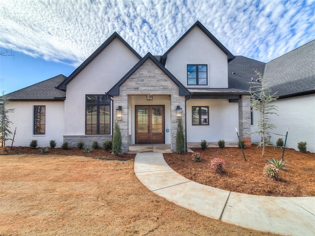 view of front of house with french doors, a shingled roof, a standing seam roof, metal roof, and stone siding