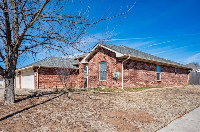 single story home with a garage, brick siding, fence, and roof with shingles