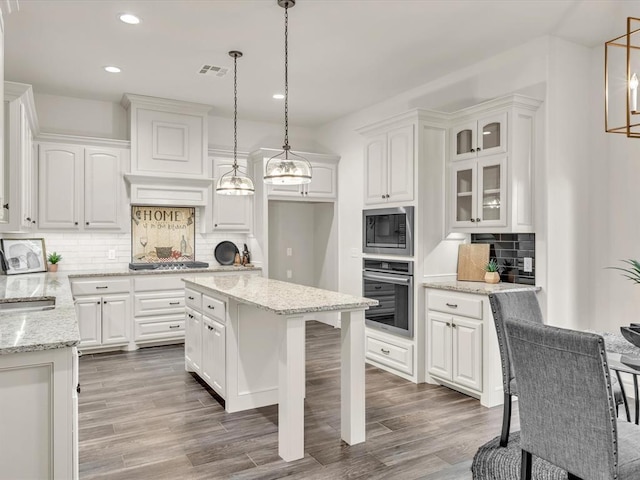 kitchen featuring light stone counters, wood finished floors, visible vents, white cabinetry, and appliances with stainless steel finishes