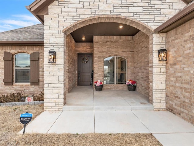 entrance to property with brick siding and roof with shingles