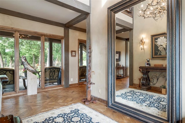 entrance foyer featuring an inviting chandelier, baseboards, and beam ceiling