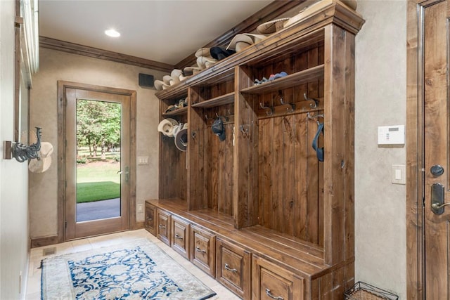 mudroom featuring light tile patterned floors and crown molding