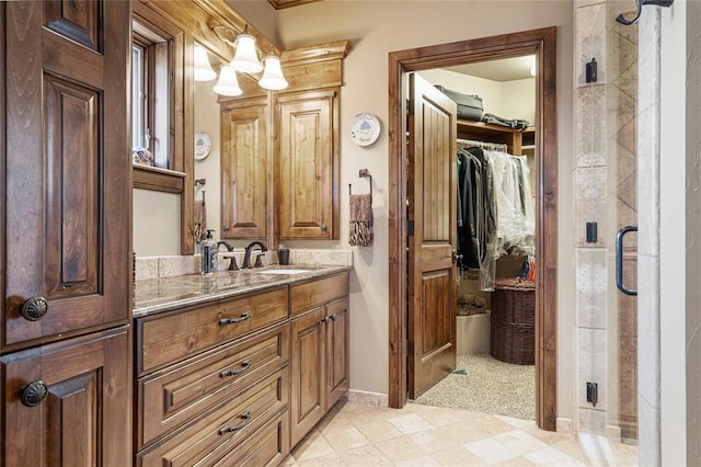 bathroom featuring a stall shower, baseboards, a walk in closet, and vanity