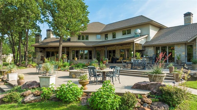 rear view of property featuring a patio area, stone siding, and a chimney