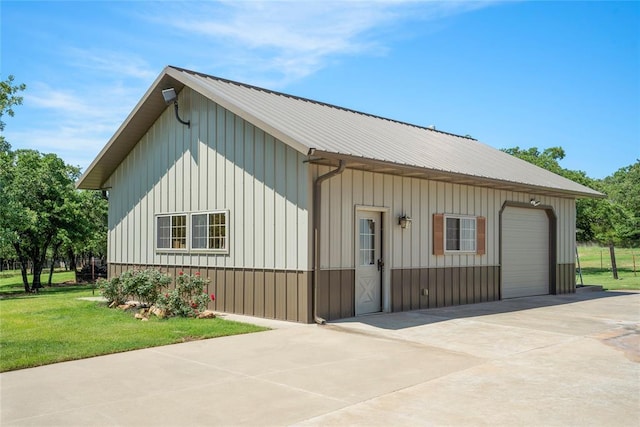 exterior space featuring an outbuilding, metal roof, board and batten siding, and a lawn