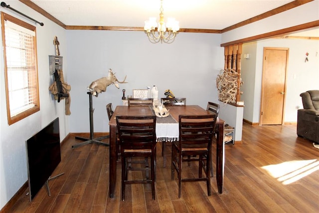 dining area featuring dark wood-style floors, ornamental molding, and a notable chandelier