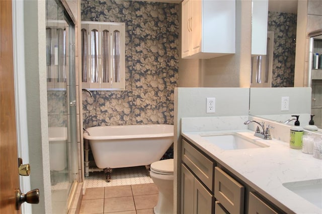 full bath featuring double vanity, wallpapered walls, tile patterned floors, a freestanding tub, and a sink