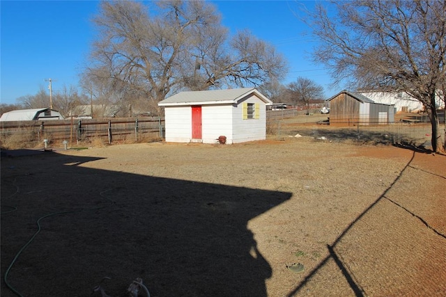 view of yard with a shed, fence, and an outbuilding