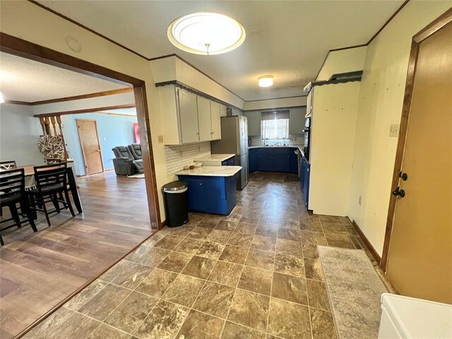 707 S Third St, Cheyenne, OK 73628 - kitchen featuring ornamental molding, a peninsula, light countertops, freestanding refrigerator, and backsplash