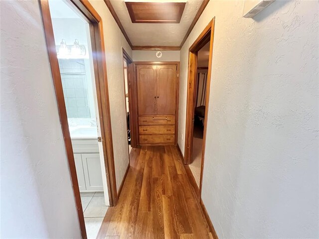 707 S Third St, Cheyenne, OK 73628 - hallway with light wood finished floors, a textured wall, and baseboards