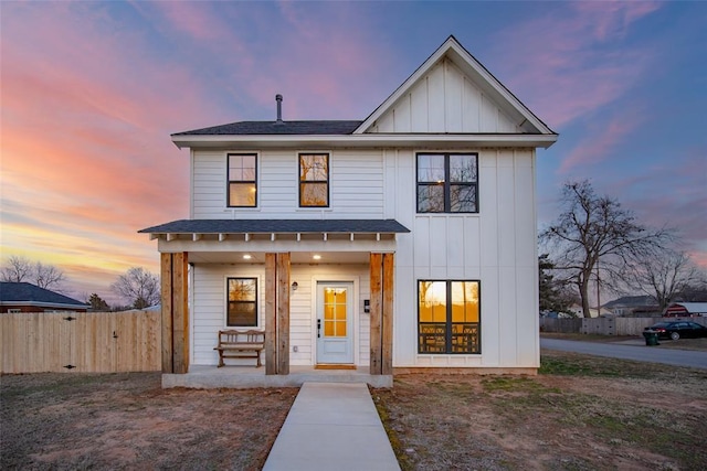 modern farmhouse style home featuring roof with shingles, covered porch, board and batten siding, a gate, and fence