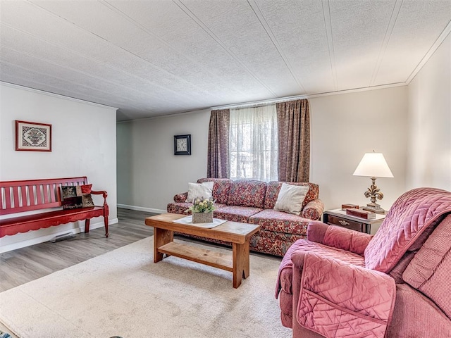 living room with crown molding, a textured ceiling, baseboards, and wood finished floors