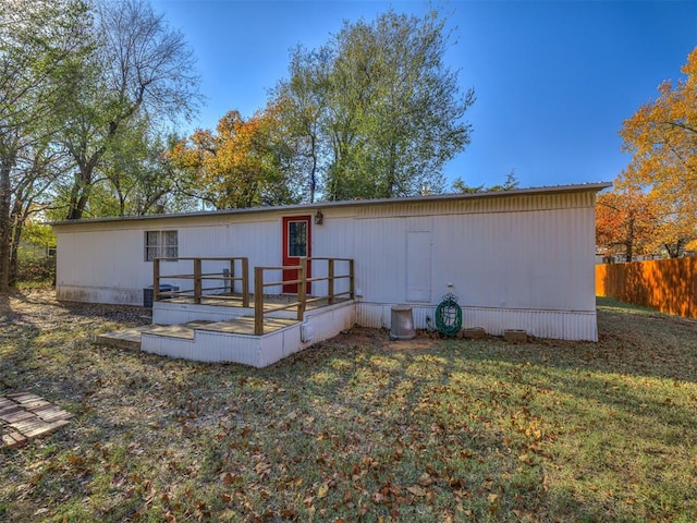 rear view of property featuring a yard, a deck, and fence