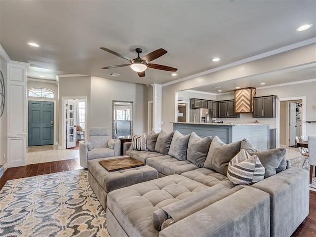 living area with light wood-style floors, recessed lighting, crown molding, and ornate columns