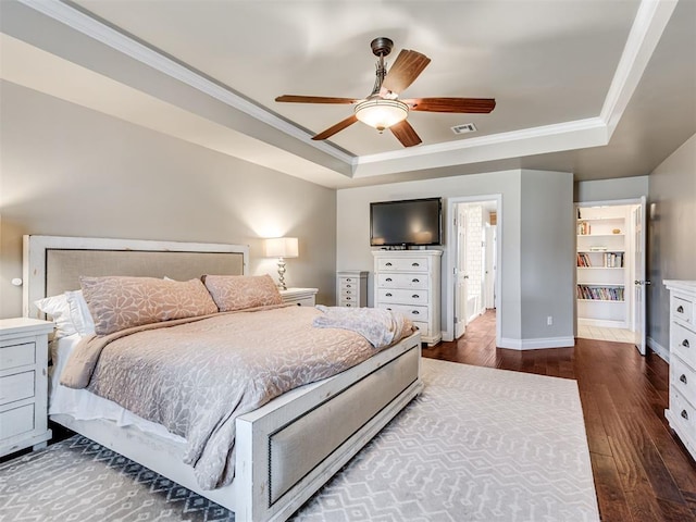 bedroom featuring baseboards, visible vents, ornamental molding, dark wood-type flooring, and a tray ceiling