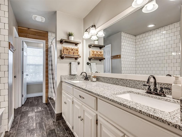 bathroom with wood finish floors, a sink, baseboards, and double vanity