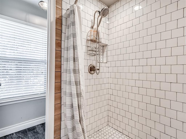 full bath with tiled shower and baseboards