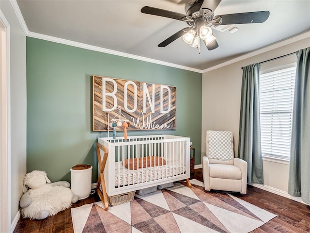 bedroom with a nursery area, crown molding, baseboards, and wood finished floors