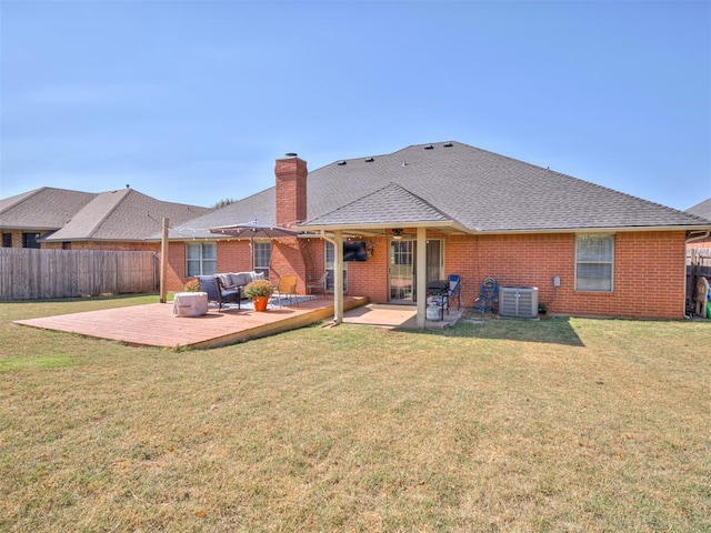 rear view of property with a lawn, a chimney, fence, central AC, and brick siding