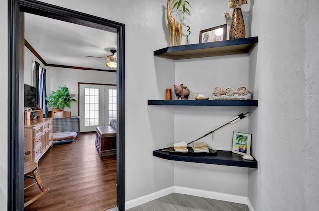 corridor featuring ornamental molding, a textured wall, baseboards, and wood finished floors