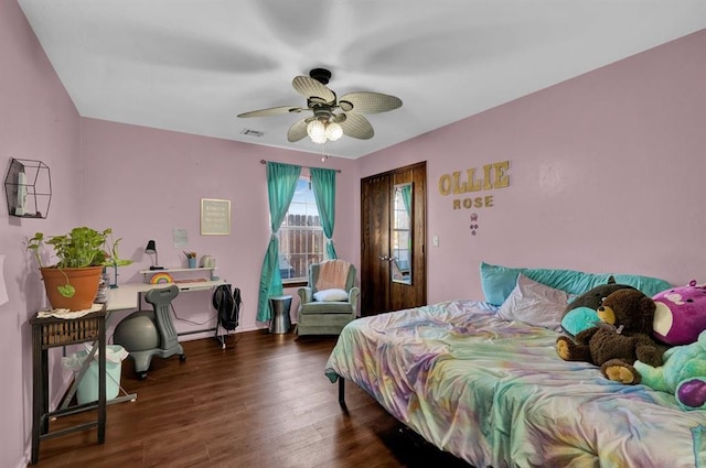 bedroom with dark wood-type flooring, a ceiling fan, visible vents, and baseboards