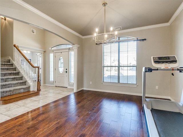 entrance foyer with visible vents, ornamental molding, light wood-type flooring, ornate columns, and stairs