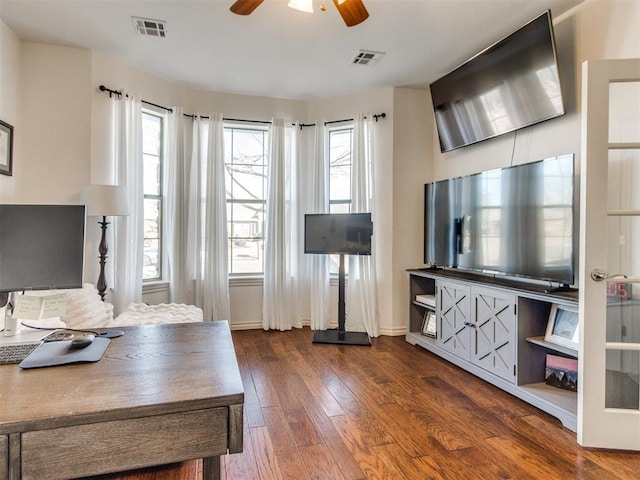 living area with dark wood-style flooring, visible vents, and baseboards