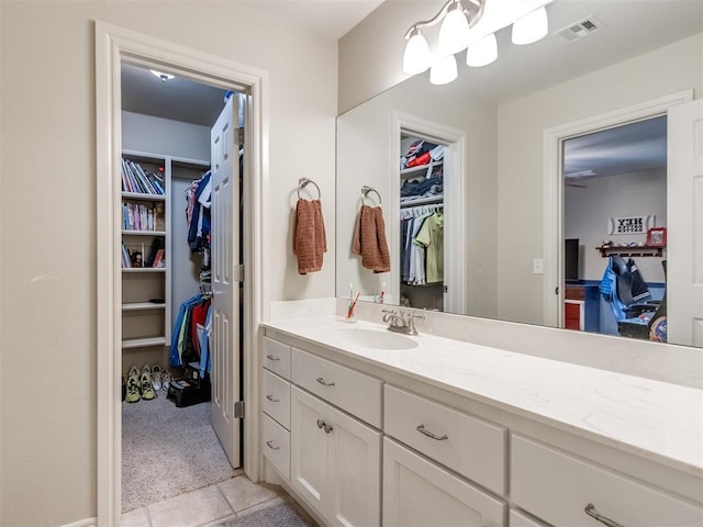 bathroom featuring a walk in closet, visible vents, vanity, and tile patterned floors