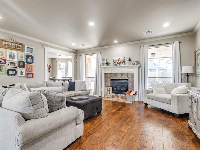 living area with dark wood-style flooring, crown molding, recessed lighting, visible vents, and a tile fireplace