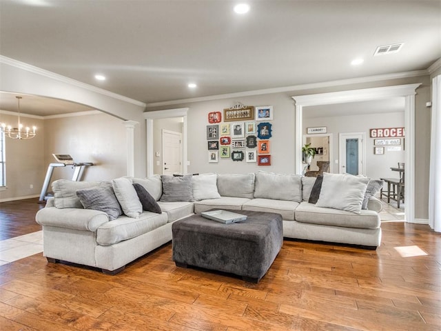 living area featuring decorative columns, a notable chandelier, recessed lighting, visible vents, and wood finished floors