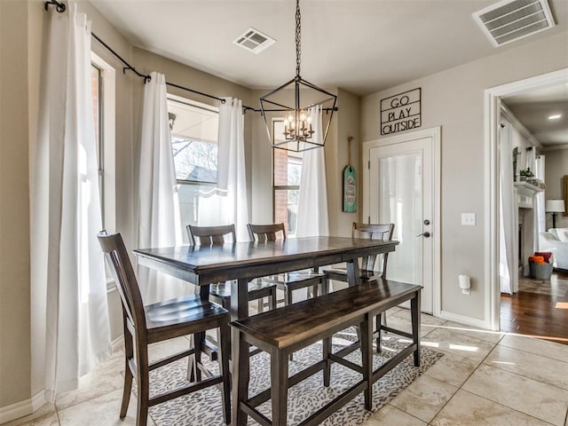 dining space with light tile patterned flooring, a fireplace, visible vents, and baseboards