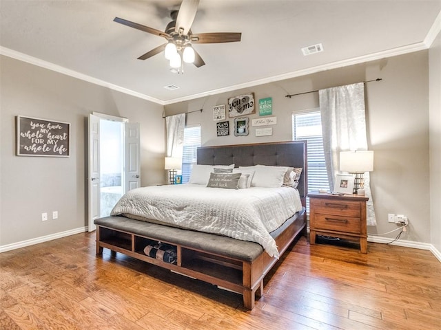 bedroom featuring baseboards, visible vents, ceiling fan, wood finished floors, and crown molding