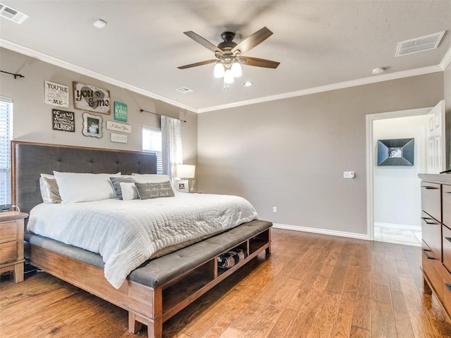 bedroom featuring ornamental molding, light wood finished floors, visible vents, and baseboards