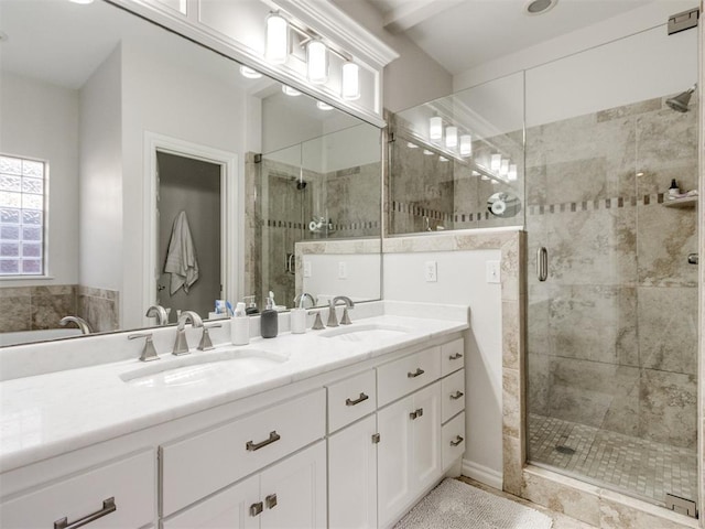 bathroom featuring double vanity, a stall shower, and a sink