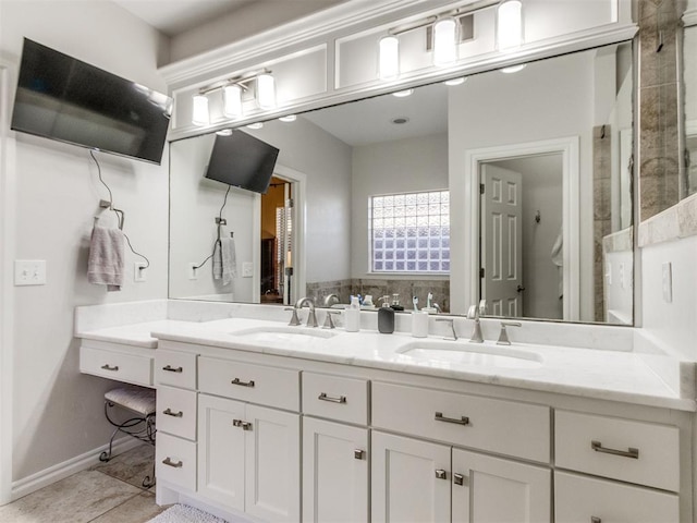 bathroom with baseboards, double vanity, a sink, and tile patterned floors