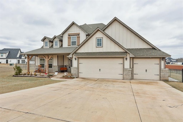 craftsman-style house featuring board and batten siding, covered porch, stone siding, and concrete driveway