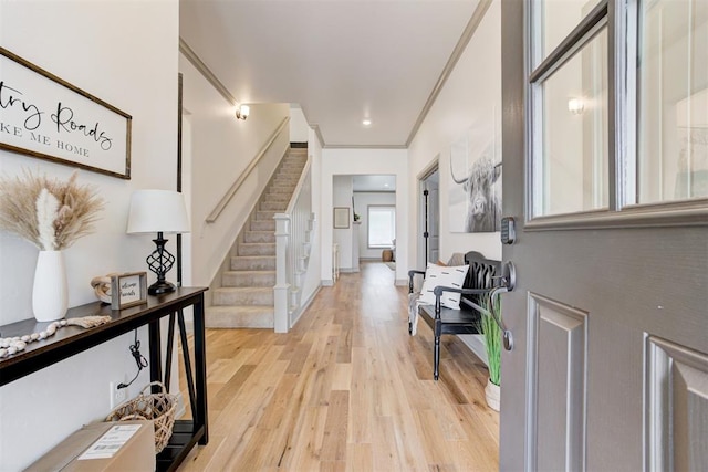 entrance foyer featuring light wood finished floors, baseboards, stairway, and crown molding