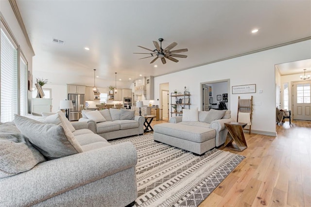 living area with visible vents, ornamental molding, ceiling fan with notable chandelier, light wood-style floors, and recessed lighting