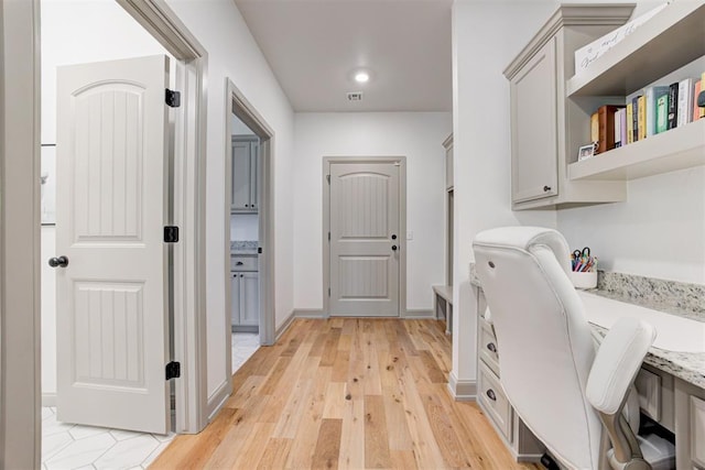 interior space featuring visible vents, light wood-type flooring, cabinet space, and baseboards