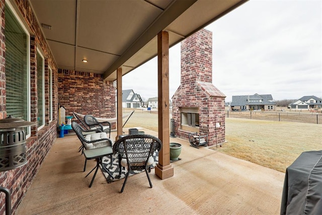 view of patio featuring an outdoor brick fireplace, fence, and a residential view